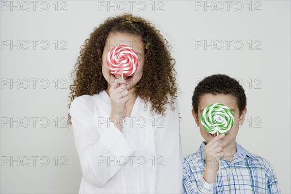 Mixed race brother and sister with oversized lollipops