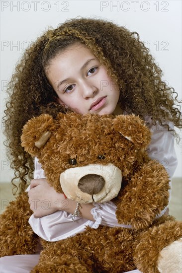 Mixed race girl in nightgown with teddy bear