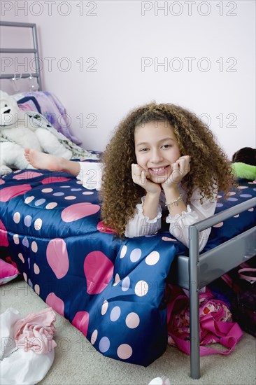 Mixed race girl laying on bed in bedroom