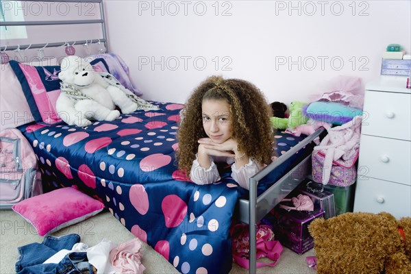 Mixed race girl laying on bed in bedroom