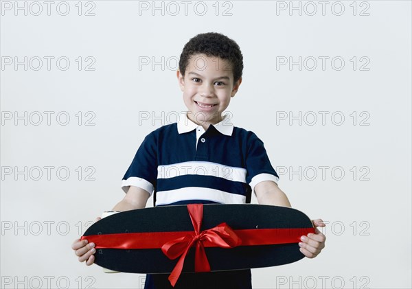 Mixed race boy holding skateboard