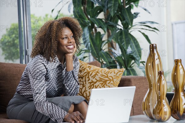 African woman daydreaming in modern living room