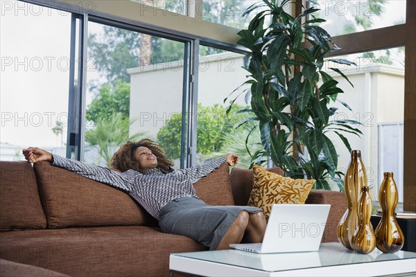 African woman relaxing on sofa in modern living room