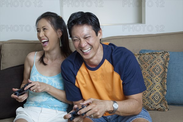Japanese couple playing video games in living room