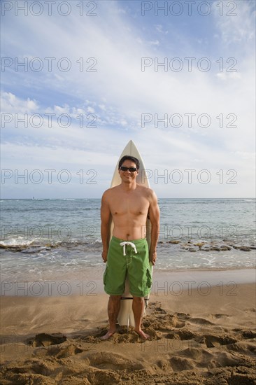 Japanese man with surfboard on beach