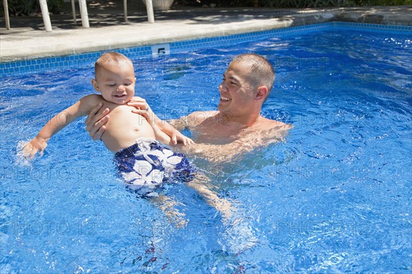 Father playing with son in swimming pool