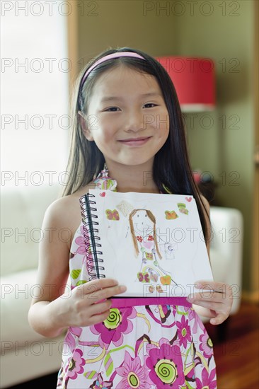 Mixed race girl holding up self-portrait drawing