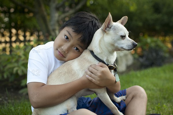 Mixed race boy hugging dog outdoors