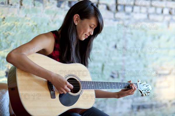 Asian girl strumming guitar