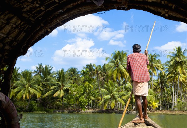 Man standing in boat on tranquil forest river