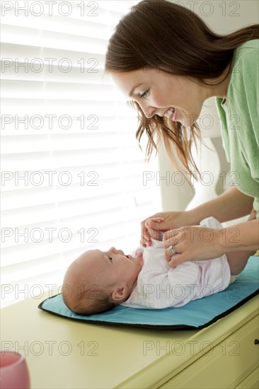 Caucasian mother changing baby daughter