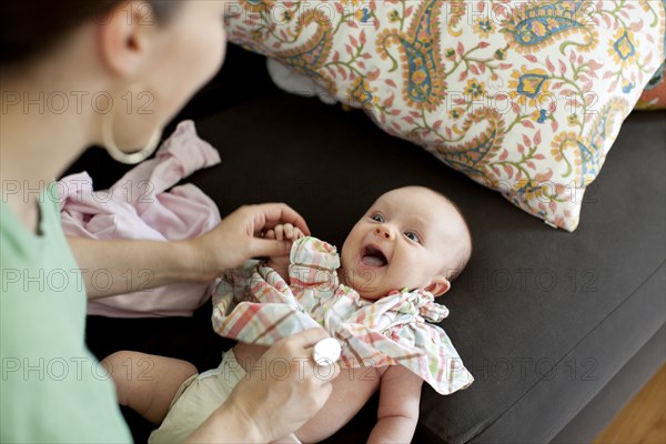 Caucasian mother changing baby daughter's clothes