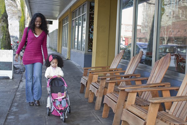 Mixed race mother and daughter walking on sidewalk