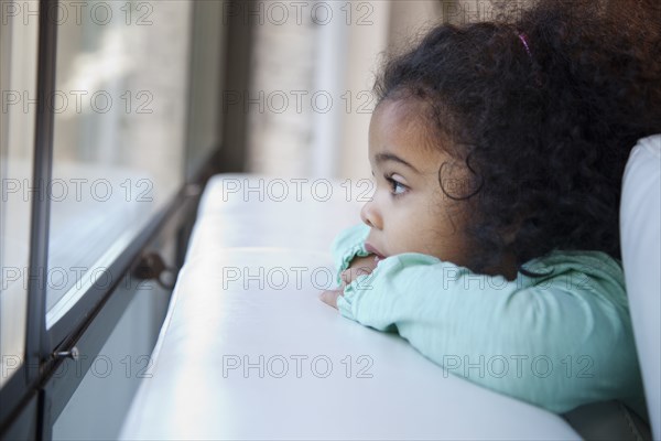 Mixed race girl looking out window