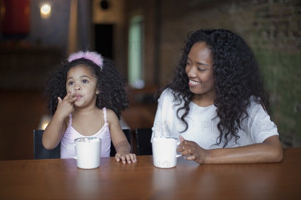 Mixed race mother and daughter drinking hot chocolate