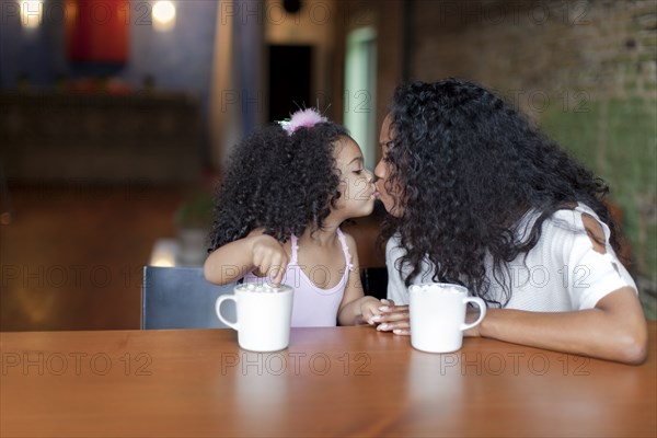 Mixed race mother and daughter kissing