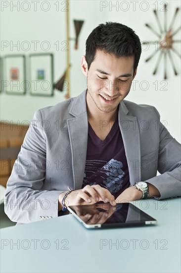 Smiling mixed race man in jacket using digital tablet