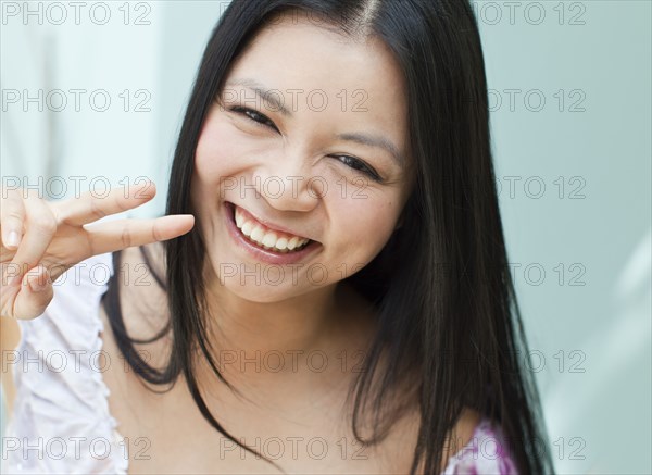 Smiling Vietnamese woman making peace sign gesture