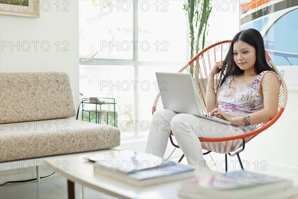 Vietnamese woman using laptop in living room