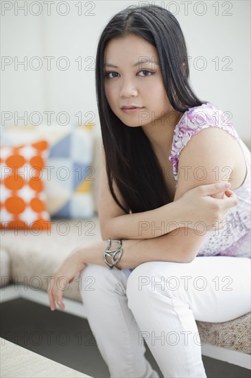 Serious Vietnamese woman sitting on sofa