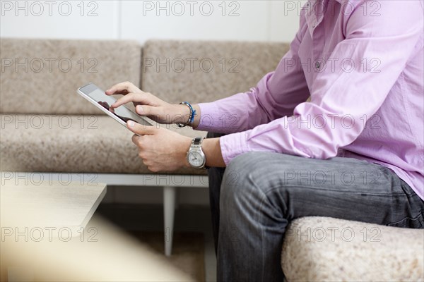 Mixed race man using digital tablet in living room