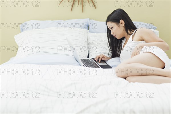 Vietnamese woman using laptop in bed