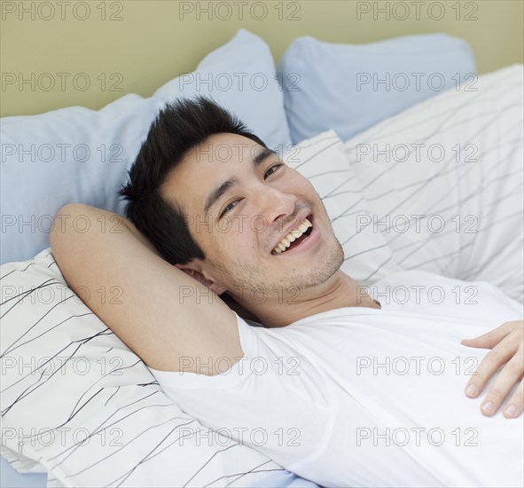 Smiling mixed race man laying in bed