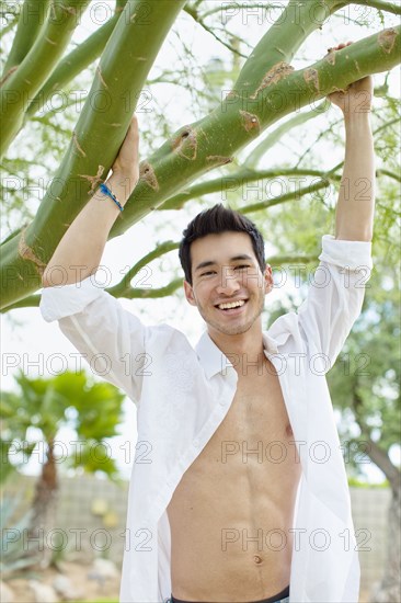 Mixed race man holding onto tree branch