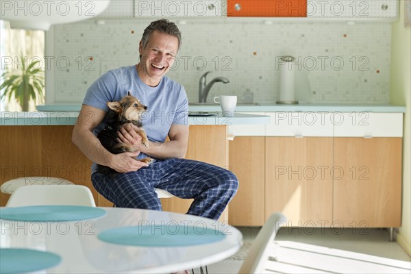 Man sitting in kitchen with dog