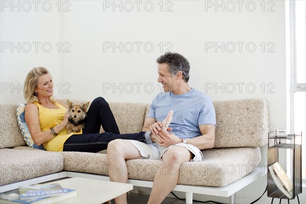 Couple relaxing with dog on sofa