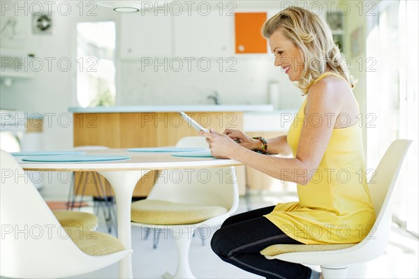 Caucasian woman using digital tablet in dining room