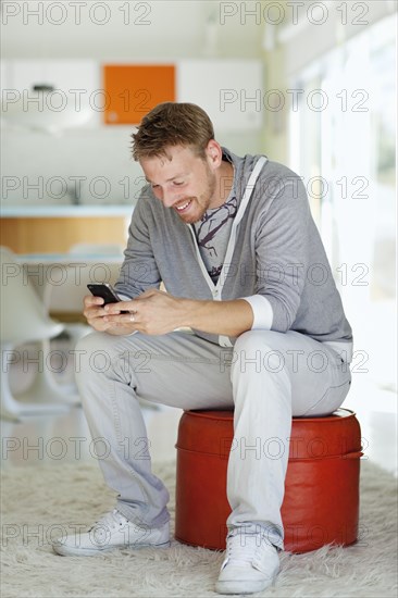 Caucasian man text messaging on cell phone in living room