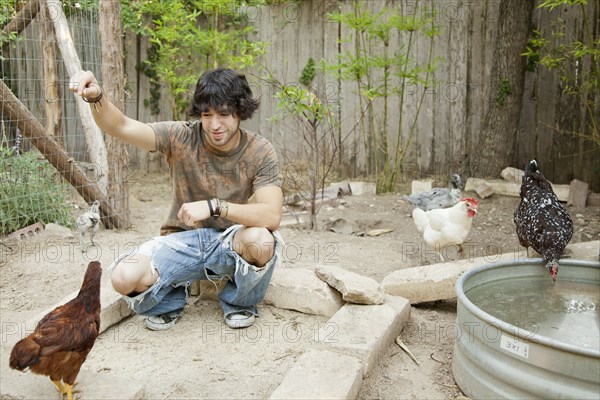 Mixed race man feeding chickens