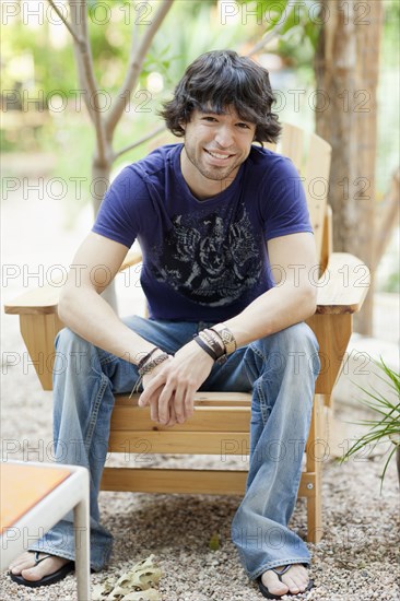 Mixed race man sitting in Adirondack chair