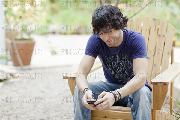 Mixed race man sitting in chair using cell phone