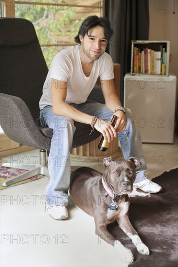 Mixed race man drinking beer and sitting with dog