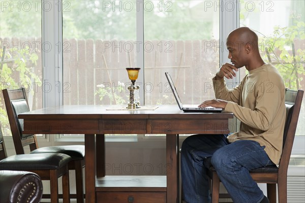 Black man using laptop at table