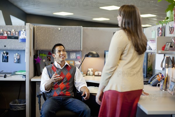 Business people talking in office cubicle