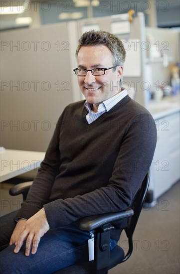 Caucasian businessman sitting at desk in cubicle