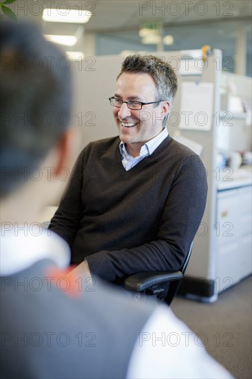 Business people talking in office cubicle