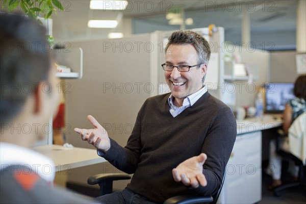 Business people talking in office cubicle