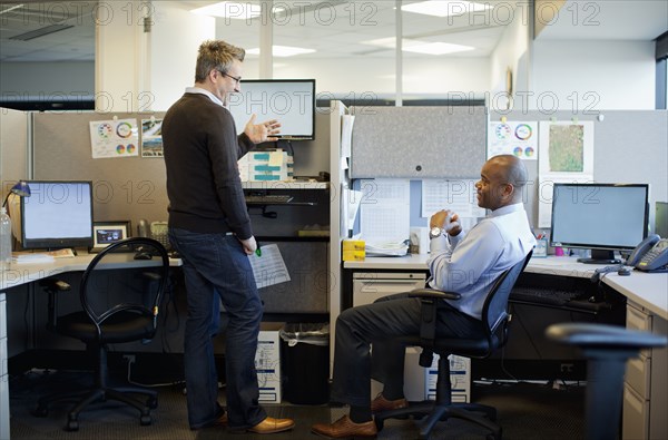 Business people talking in office cubicle