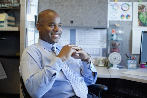 African American businessman sitting in office cubicle