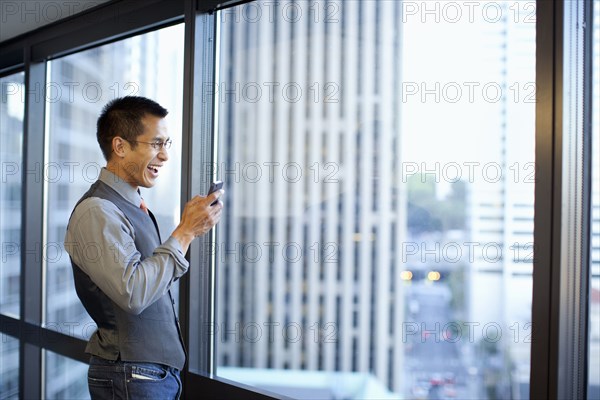 Mixed race businessman using cell phone in office