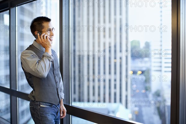 Mixed race businessman using cell phone in office