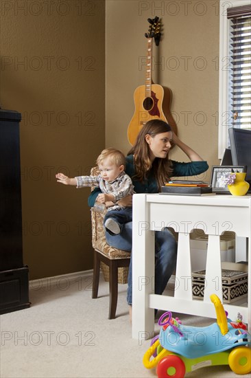 Caucasian mother using laptop and holding baby