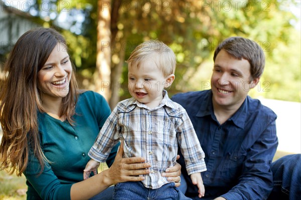 Caucasian parents sitting outdoors with son