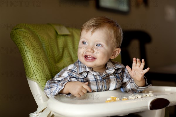 Caucasian boy eating in high chair