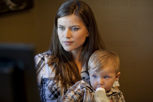 Caucasian mother using computer with son on lap