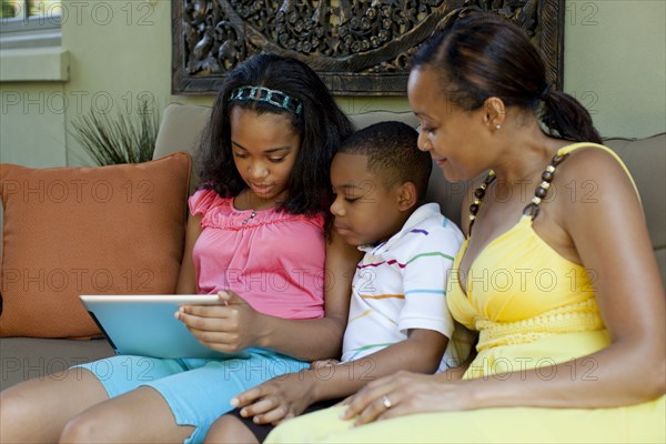 African American mother watching children with digital tablet